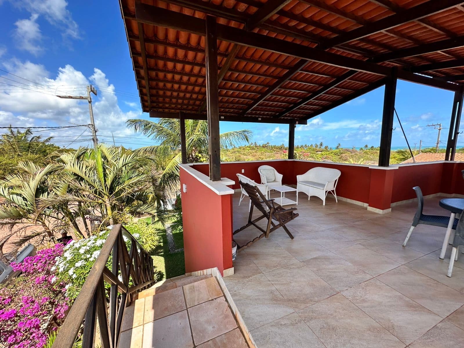 O terraço superior coberto, com o mar visível entre os coqueiros